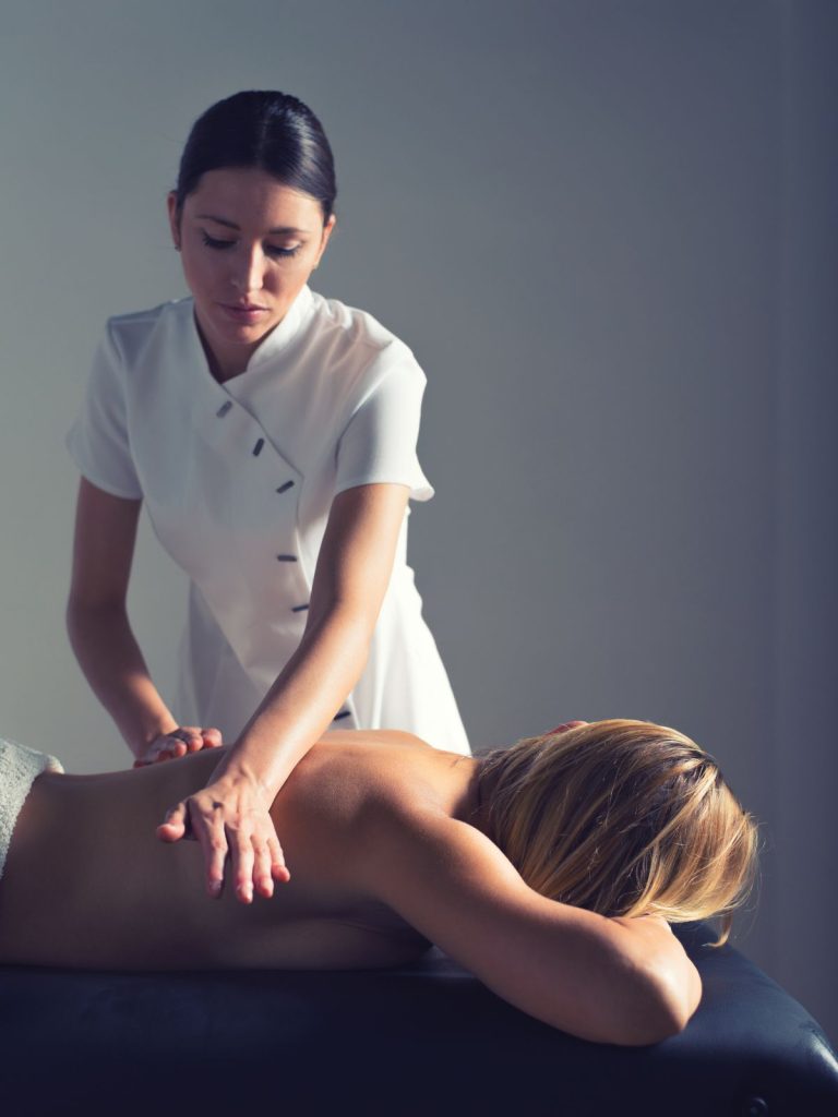 여자마사지 관리사가 누워있는 손님의 등 마사지를 하는 장면 (2)